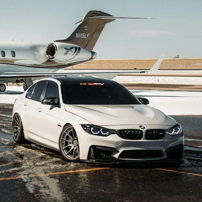 Executive Cars for Airport Transfer A sleek white BMW parked beside a private jet on a tarmac.