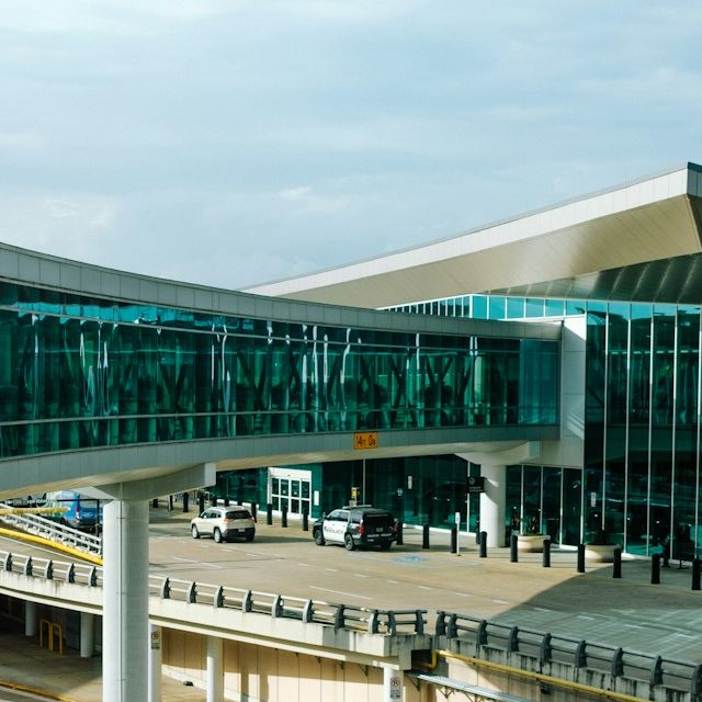 Crystal Cars Airport Transfers in Gatwick Airport Modern airport terminal with a glass walkway and parked vehicles.