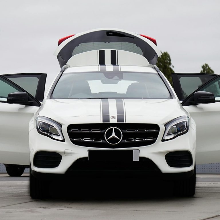 Executive MPV for Airport Transfer A white Mercedes car with open doors and black racing stripes.
