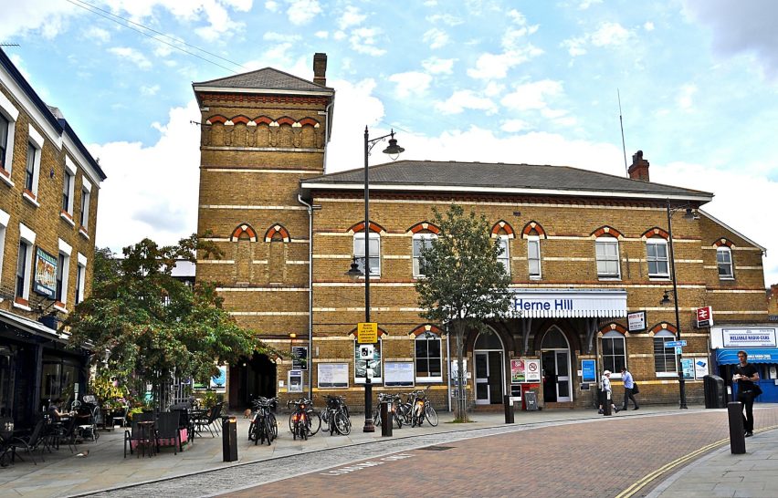 Taxi Services in Herne Hill SE24 Victorian-style building with brick facade and tower, featuring shops and vibrant street life.