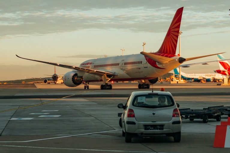 Crystal Cars Airport Transfers Airplane parked at the airport with a car in the foreground and another plane in the background.