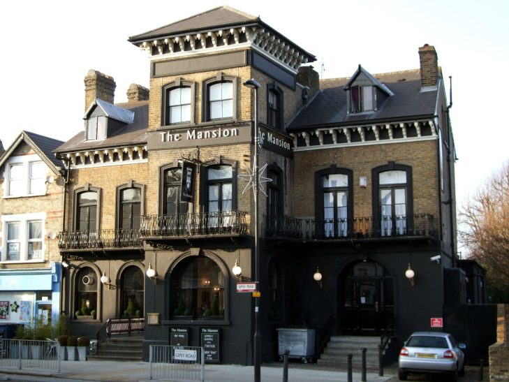 Taxi Service in West Dulwich, SE21 A large, Victorian-style building with a dark facade and balconies, housing a pub.